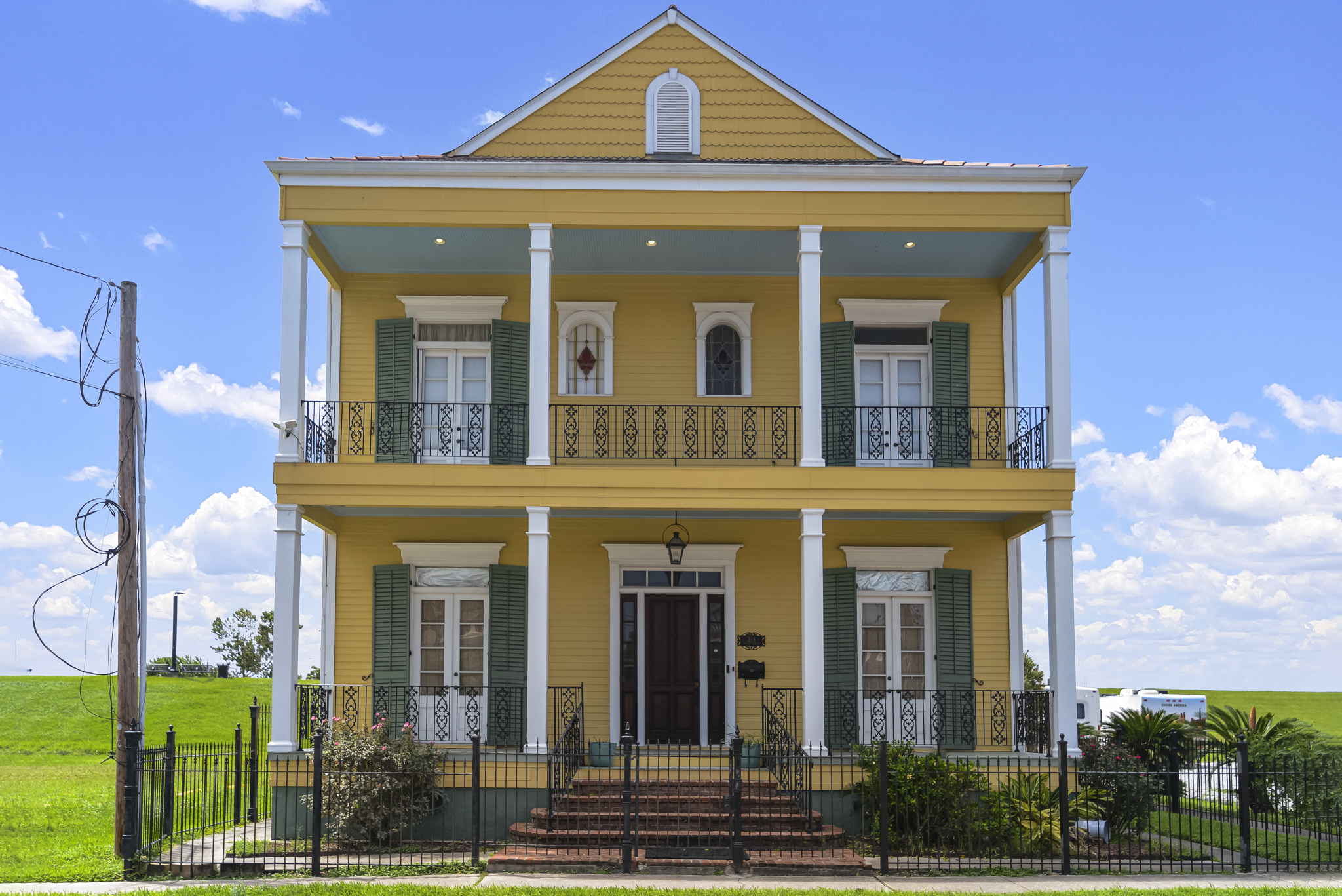 Restored two-story Creole townhouse with green shutters and double galleries in New Orleans